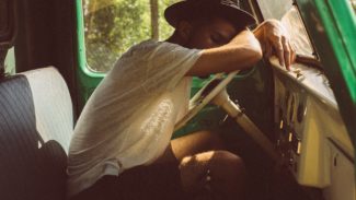 Photo of someone leaning forward to sleep against a car steering wheel