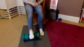 Person sat on a chair with foot on a foam roller