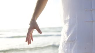 Ocean in the background and the sun is shining on a man wearing white