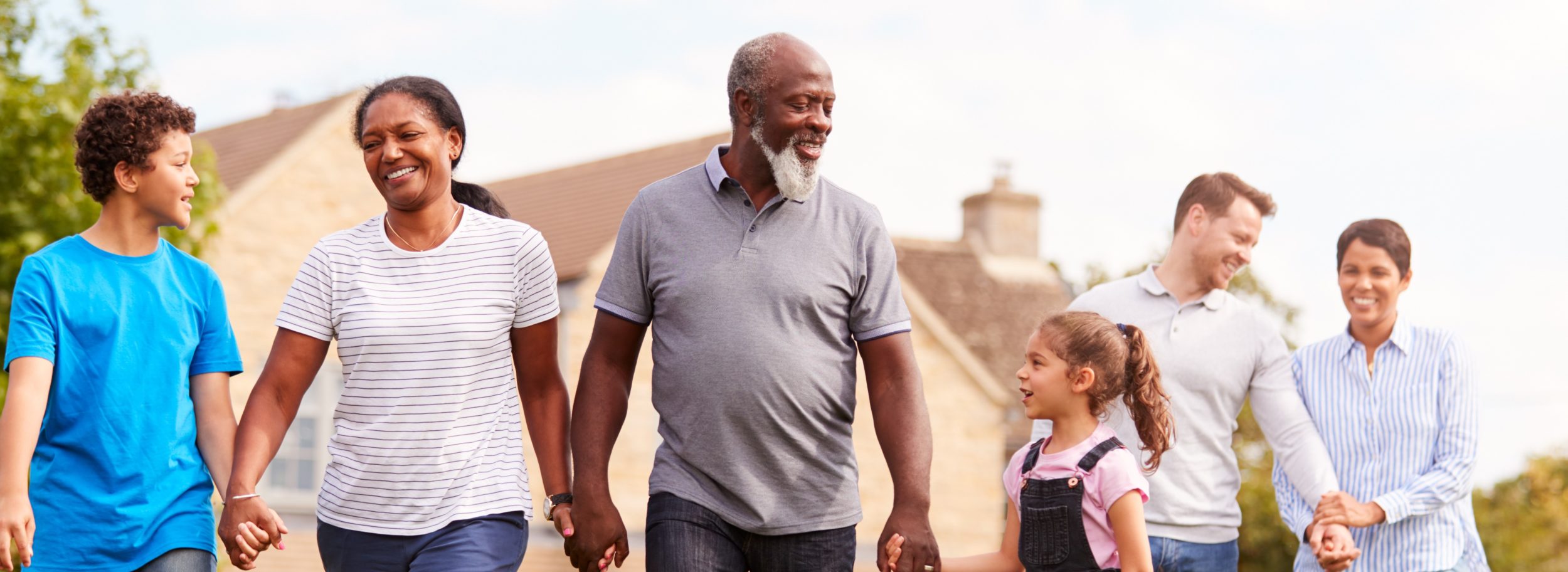 Smiling Multi-Generation Mixed Race Family Walking In Garden At Home