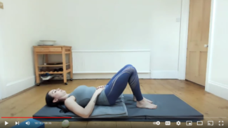 Ruth lying on her back on a mat, knees bent and arms resting on her belly