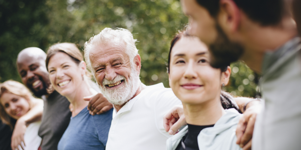 A group of people linking shoulders and smiling at each other