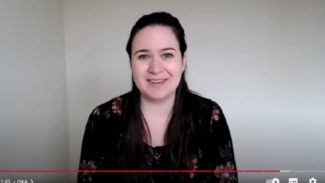 Screenshot of Zoë talking to the camera, wearing a black long sleeved top