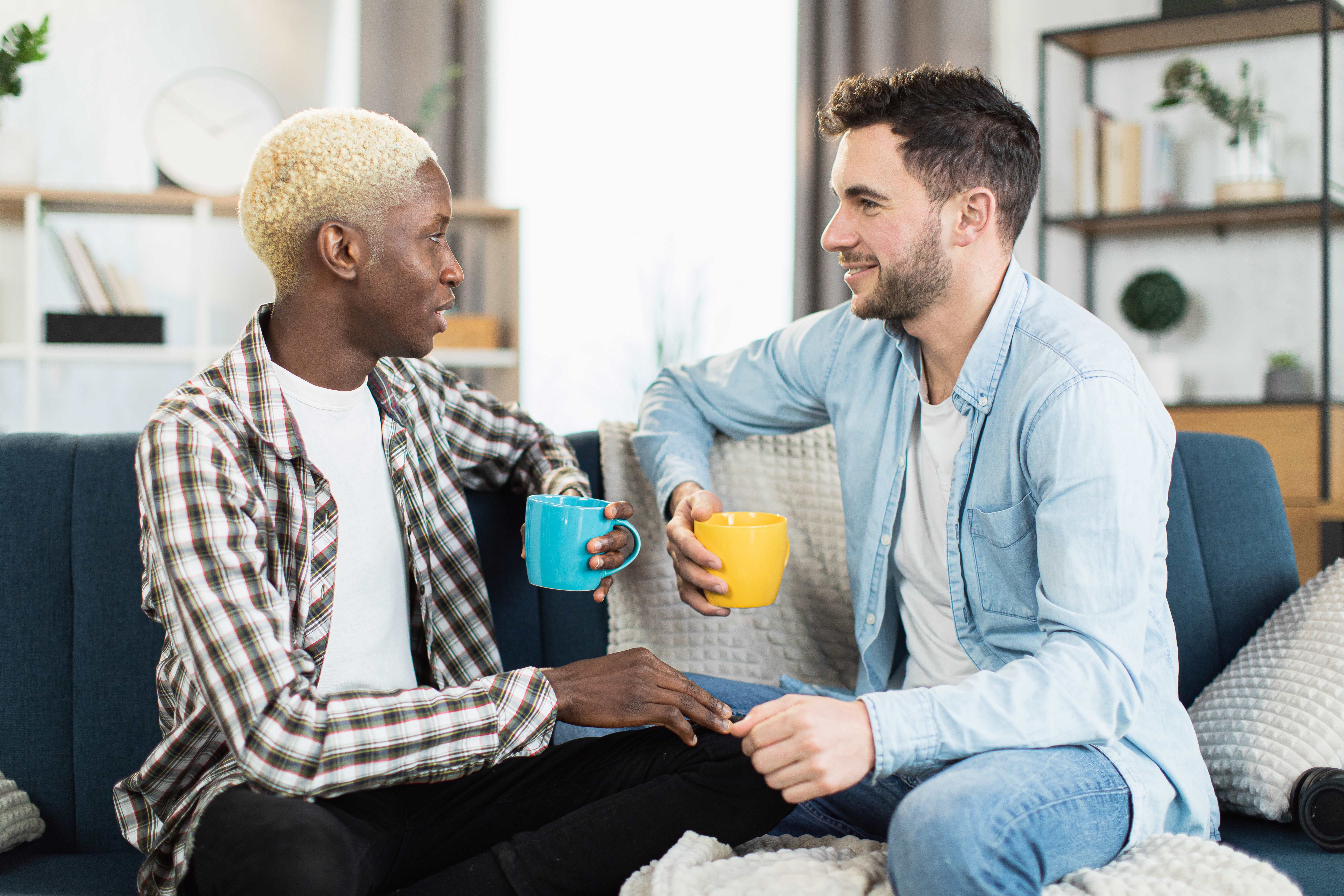 Two men sat chatting with mugs in their hands